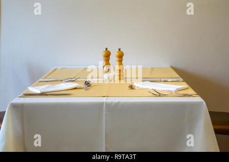 Minimalistischer Tisch im Restaurant mit einfachen Tischdecke, Besteck, Servietten und Salz und Pfeffer Mühlen vor weißem Hintergrund, kopieren Raum Stockfoto