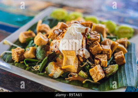 Gado - gado Indonesischer Salat mit Erdnusssoße. Zutaten: Tofu, Spinat, Bohnen, Soja Sprossen, Kartoffeln, Gurken und gekochte Eier. Stockfoto