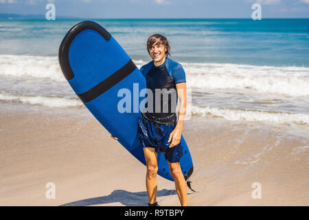 Mann, Surfbrett über seinen Kopf. Nahaufnahme von hübscher Kerl mit Surfbrett auf dem Kopf am Strand. Portrait von Mann Surfboard auf hid Kopf und an Strand lächelnd Stockfoto