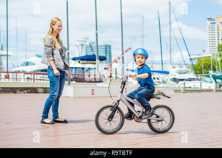 Mama lehrt Sohn ein Fahrrad im Park zu fahren Stockfoto