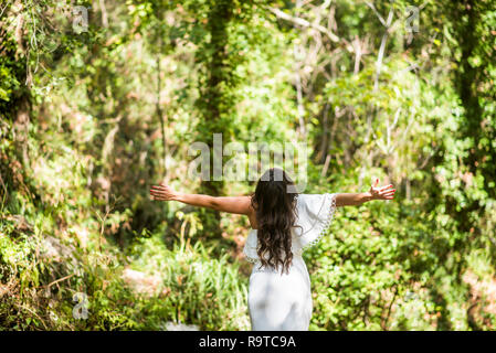 Rückansicht einer Frau, die Arme im Wald oustretched Stockfoto