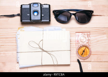 Vintage Kamera, Sonnenbrille, Bündel Briefe und einen Kompass auf einem hellen, natürlichen Holz- Hintergrund. Sommer Zubehör. Flach Ansicht von oben. Stockfoto