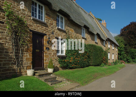 Reihe von malerischen, aus Stein gebauten strohgedeckten Hütten im Dorf Ashby St Ledgers, Northamptonshire, Großbritannien Stockfoto