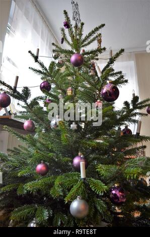 Geschmückten Weihnachtsbaum im Wohnzimmer, Silber und violett Kugel Dekorationen auf eine grüne Tanne Stockfoto