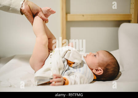 Mutter ändern windel baby, ihre kleinen Beine anheben. Stockfoto