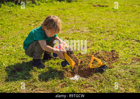 Der junge spielt Recycling. Er begräbt Plastik Einweggeschirr und biologisch abbaubare Gerichte Stockfoto