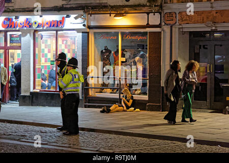 Im Bild: Eine Frau sitzt auf dem Bürgersteig. Freitag, 14 Dezember 2018 Re: Nachtschwärmer in der Wind Street, Swansea, Wales, UK. Stockfoto