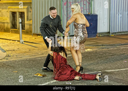 Im Bild: Eine Frau ist zu ihren Füßen, die von einem Mann und einer Frau geholfen. Freitag, 14 Dezember 2018 Re: Nachtschwärmer in der Wind Street, Swansea, Wales, UK. Stockfoto