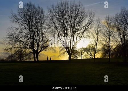 Schönen Sonnenuntergang Landschaft an einem kalten Winterabend in Hampstead Heath im Norden von London. Zwei Personen sind in der Ferne zu sehen. Stockfoto