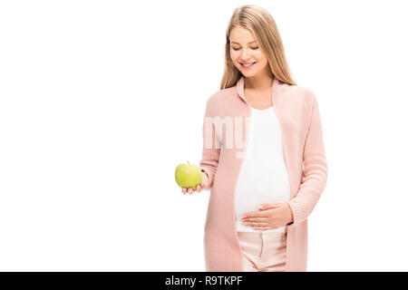 Schöne schwangere Frau mit grünem Apfel und lächelnd auf Weiß isoliert Stockfoto