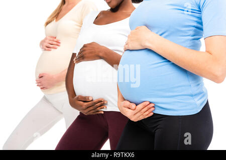 7/8-Ansicht von drei schwangere Frauen, Hände auf Bauch isoliert auf weißem Stockfoto