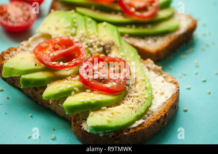 Frische leckere Toasts mit Avocado, Tomaten in Scheiben geschnitten und gehören insbesondere Samen. Gesunde Ernährung Konzept. Stockfoto