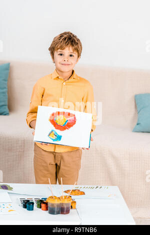 Adorable Happy Boy holding Bild und lächelnd an Kamera Stockfoto