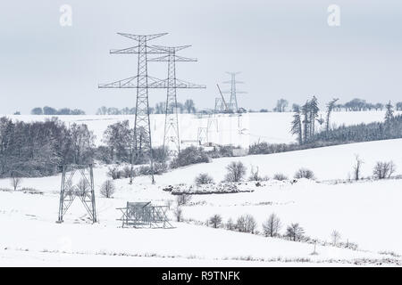 Bau von Hochspannungsmasten im Winter. Montiert Power Transmission Line unterstützt, bereit für die Installation. Stockfoto