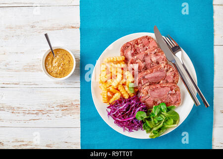 Geschnetzeltes Sülze rind Zunge mit Pommes frites, grüne Blätter und Rotkohl Salat auf einem weißen Teller auf einen hölzernen Tisch serviert mit Senf in einer Schüssel, vi Stockfoto