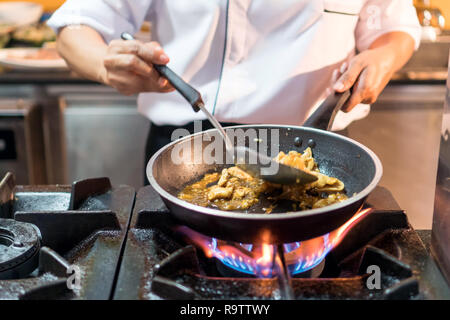 Koch Kochen Thai Food Küche in Skillet über Flammen auf Gas Herd Stockfoto