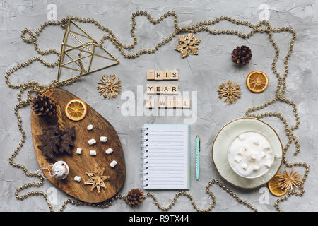 Dieses Jahr werde ich Wörter, Notepad und blauen Stift auf einem grauen Hintergrund, goldenen Dekorationen und Cookies. Ansicht von oben, flach, mockup. Winter, Weihnachten zu tun Stockfoto