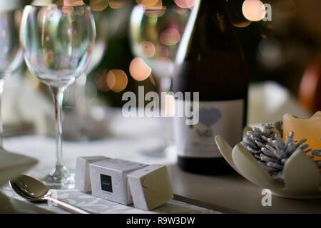 Weingläser und eine Flasche Asti mit Weihnachtsbeleuchtung im Hintergrund Stockfoto