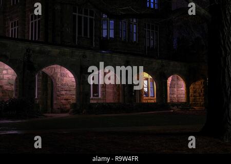 Nächtlicher Blick von außen von einem schwach gewölbten Korridor der Heiligen Kapelle an der Universität im Süden in Sewanee, Tennessee beleuchtet. Stockfoto