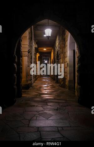 Blick von Außen durch larged Torbogen einer spärlich beleuchteten Korridor an der alle Heiligen Kapelle an der Universität im Süden in Sewanee, Tenn Stockfoto