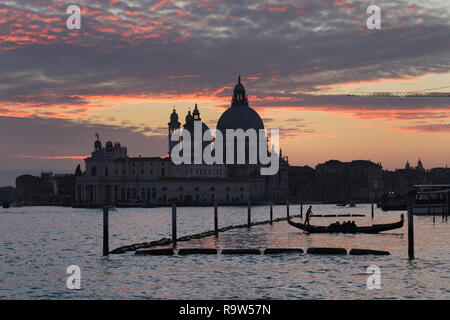 Gondel bei Sonnenuntergang in der Lagune von Venedig (Laguna di Venezia) vor der Basilika von Santa Maria della Salute (Basilica di Santa Maria della Salute) in Venedig, Italien. Stockfoto