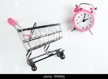 Weibliche einkaufen. Warenkorb und Wecker rosa Farbe auf weißem Hintergrund. Stockfoto