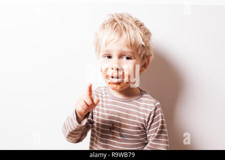 Junge eated Schokolade und mehr essen möchte Stockfoto