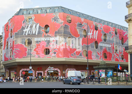 PARIS, Frankreich, 07.Juli 2018: HM store Gebäude mit Menschen rot Blumenschmuck Fassade in Paris. Stockfoto