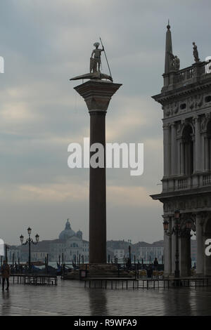 Spalte von Saint Theodore (Colonna di San Todaro) In Piazzetta di San Marco in Venedig, Italien. Die Kirche von Santa Maria della Presentazione (Chiesa di Santa Maria della Presentazione) auch als Le Zitelle Kirche (Chiesa delle Zitelle) auf der Insel Giudecca in im Hintergrund zu sehen. Stockfoto