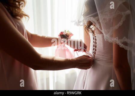 Hilft die Braut ihr Brautkleid anziehen Stockfoto