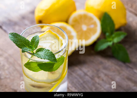 Zitronenwasser mit frischen Zitronen und grüner Minze auf Tisch Stockfoto