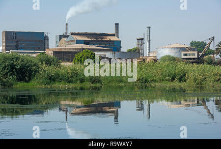 Blick über den großen Fluss Nil in Ägypten durch die ländliche Landschaft mit indutrial Zuckerrohr Fabrik verursacht Verschmutzungen Stockfoto