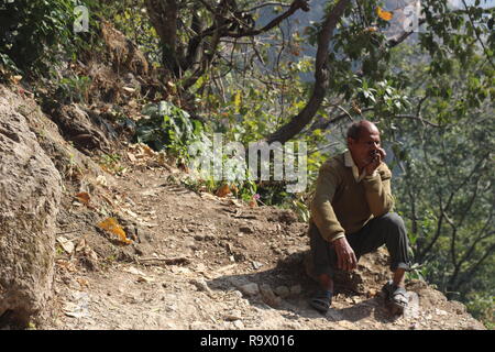 Ein alter Mann gesehen sitzen auf einem Hügel und Trekking nach Neer jharna in Rishikesh, Uttarakhand, Indien Stockfoto