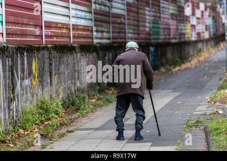 Alter Mann geht langsam, lehnte sich auf einen Spazierstock, Stockfoto