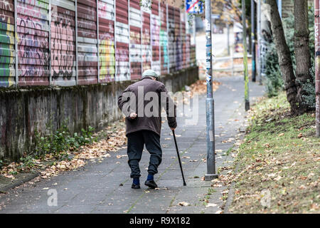 Alter Mann geht langsam, lehnte sich auf einen Spazierstock, Stockfoto