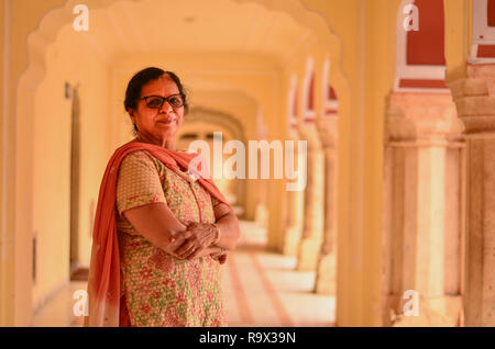 Glücklich auf der Suche älteren indischen Frau in traditioneller Anzug posiert im Flur der Stadt Jaipur Palace. Stockfoto