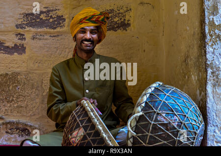 Jodhpur, Rajasthan, Indien, 2019. Lächelnd rajasthani Spieler in traditionellen pagdi Schlagzeug spielen in Mehrangarh Fort Drum. Stockfoto
