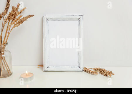 Vertikale Rahmen mockup mit wilden Roggen Blumenstrauß in glass vase in der Nähe von weißen Wand. Leeren Rahmen mock up für Presentation Design. Vorlage framing für moderne Ar Stockfoto