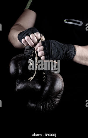 Zwei sehr alte Boxen Sport Handschuhe in der Menschen Hände zurückgespult mit einem schwarzen Verband Stockfoto