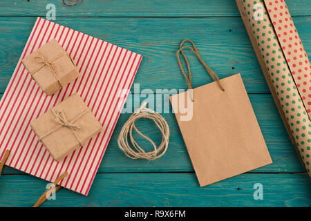 Celebratory Konzept - mit handgefertigten gestreifte Shopping Bag, Geschenkbeutel, Verpackung Papier mit Polka Dots auf Blau Holz- Hintergrund Stockfoto