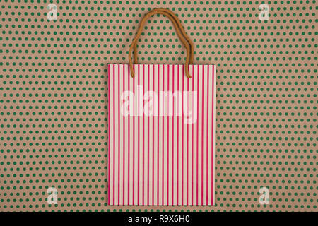 Celebratory Konzept - Handgemachte gestreifte Shopping Bag, Geschenkbeutel für das Handwerk Papier Hintergrund in grün Polka Dots Stockfoto