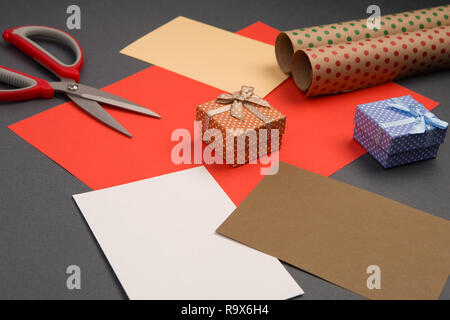 Celebratory Konzept - geschenkboxen in Polka Dots, Verpackung Papier, farbiges Papier und Schere auf grauem Hintergrund Stockfoto