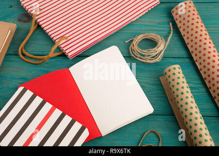 Feierlich und Bildung Konzept - mit handgefertigten gestreifte Shopping Bag, Verpackung Papier mit Polka Dots, Notizblöcke auf Blau Holz- Hintergrund Stockfoto