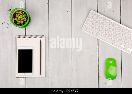 Wireless slim White Keyboard und Maus grün, Smartphone, Notepad, Blume auf weißem Holz- Hintergrund Stockfoto