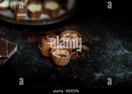 Verschiedene, süße Pralinen von Zartbitter-, Vollmilch- und weißer Schokolade in einer dunklen, hölzernen Hintergrund Stockfoto