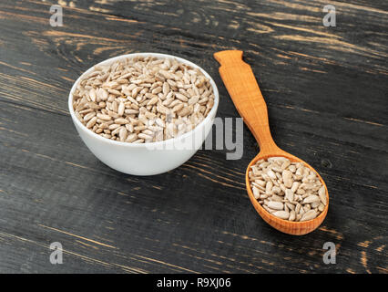 Sonnenblumenkerne ohne Schale, Löffel und Schüssel auf Holz- Hintergrund Stockfoto