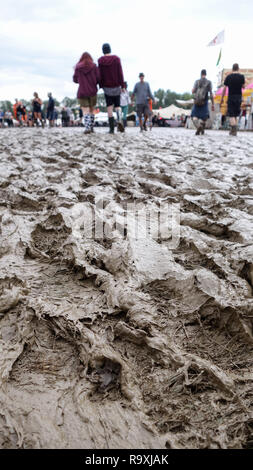 Gras wandte sich Schlamm an einem kalten Festival, mit Leute in Stiefeln im Hintergrund Stockfoto