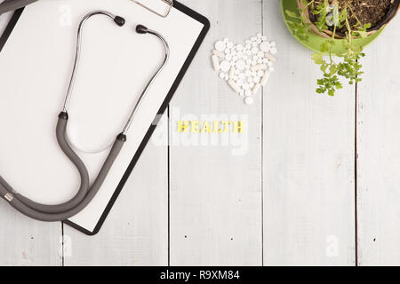 Medizinisches Konzept - Stethoskop, pad, Flasche, Weiß Herz von Pillen und Kapseln, Gesundheit Beschriftung auf weißem Schreibtisch aus Holz Stockfoto