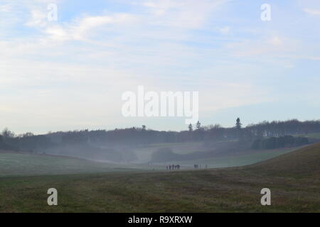 Eine Familie in der Mitte der Entfernung auf einen post Weihnachten Spaziergang an lullingstone Country Park, 27 Dezember, 2018 wie Nebel Formen in das Tal. Kent, England Stockfoto