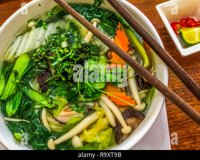 Pflanzliche Pho Suppe in Vietnam mit frischen Champignons, Karotten, Bok Choy und Stöcke auf einer hölzernen Tisch chop Stockfoto